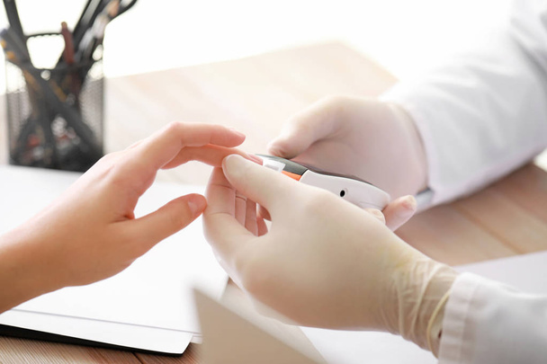 Doctor controle bloedsuikerspiegel van diabetische vrouw in kliniek, close-up - Foto, afbeelding
