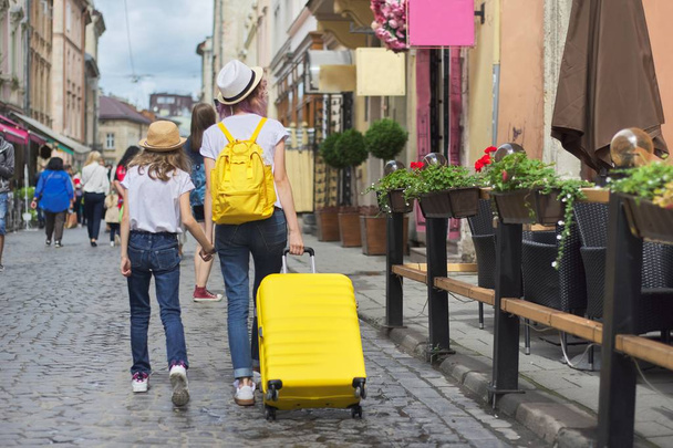 Two girls walking in city with suitcase, back view - Zdjęcie, obraz