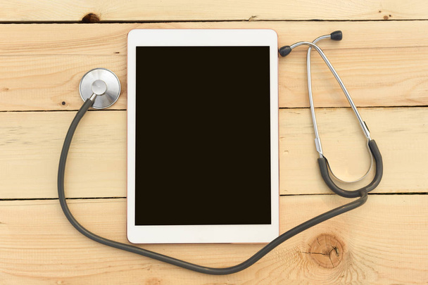 Stethoscope and tablet on wooden background. The concept of technology and medicine, distant treatment, health. Top view image. Copy space for text. - Foto, Bild