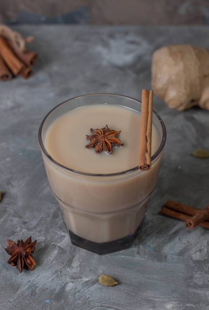 Traditional indian masala tea with ingredients. Cinnamon, cardamom, anise, ginger. On a gray background, vertical orientation.  - Foto, Imagem