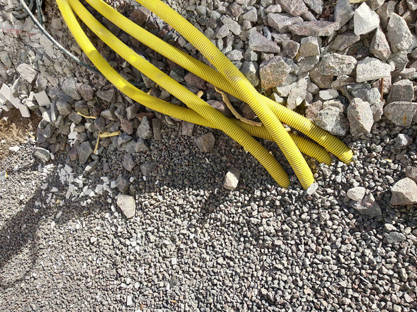 Tubos amarelos para cabos elétricos ou água colando do grou
 - Foto, Imagem
