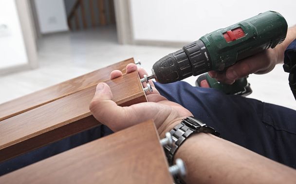 The man is assembling wooden furniture in home - Photo, image