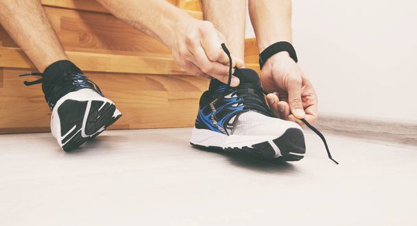 The young man is preparing for morning running and laces sneaker - Foto, Imagem