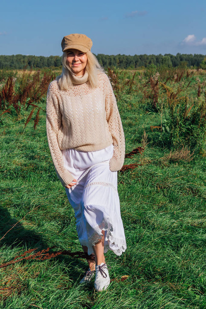 Happy beautiful blond woman walking in a green field - Fotó, kép