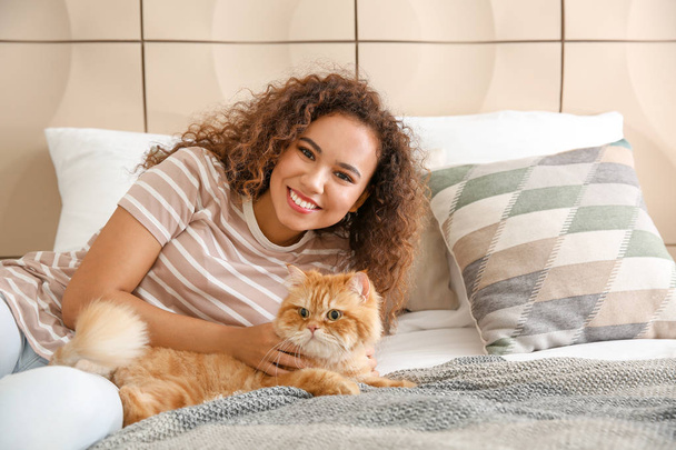 Young African-American woman with cute cat at home - Fotó, kép