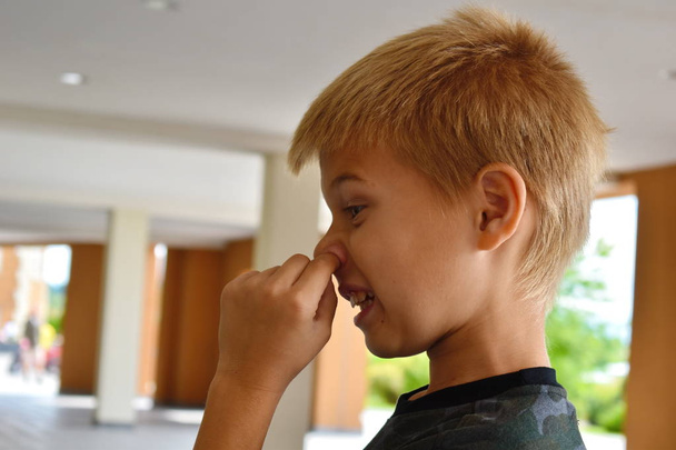 The boy pokes his nose with his finger. The child pulls out the  - Фото, зображення