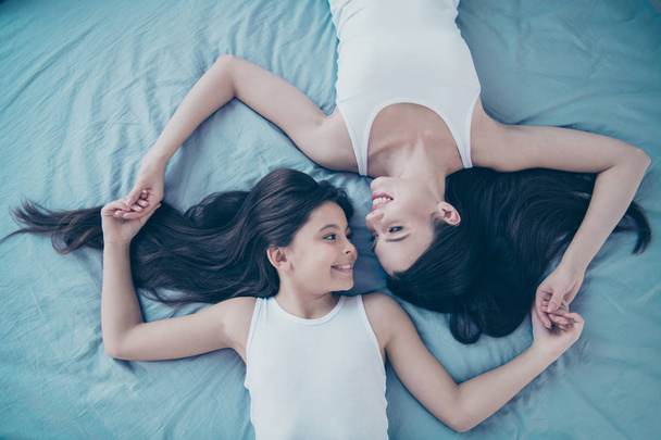 Top above high angle view portrait of two nice beautiful attractive lovely tender sweet gentle charming cute feminine kind careful cheerful people spending free spare time holiday lying on blue linen - Fotoğraf, Görsel