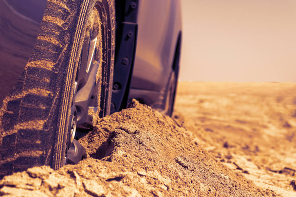 Автомобильные колеса на морском песке. Крупный план колеса автомобиля на песчаных дюнах. Машина застряла в песке. Вращающееся колесо автомобиля, застрявшего в песке
. - Фото, изображение
