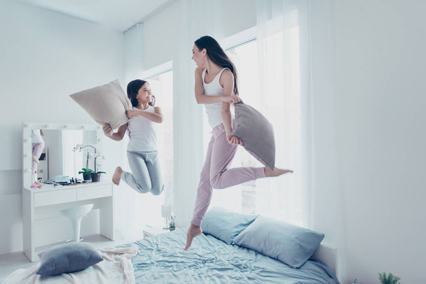 Two beautiful attractive lovely cheerful cheery careless carefree crazy people having fun spending holiday free time in modern light white interior room house indoors - 写真・画像