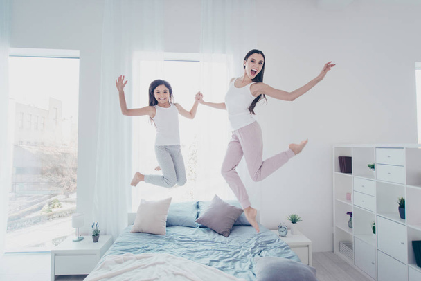 Two beautiful attractive lovely cheerful cheery careless crazy overjoyed people having fun spending holiday in modern light white interior room house indoors - Photo, image
