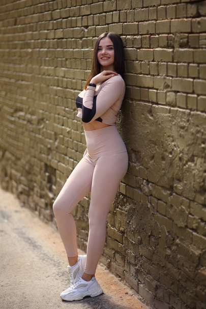 Uma jovem demonstra belas roupas esportivas em um ambiente urbano. Uma jovem no belo sportswear
. - Foto, Imagem