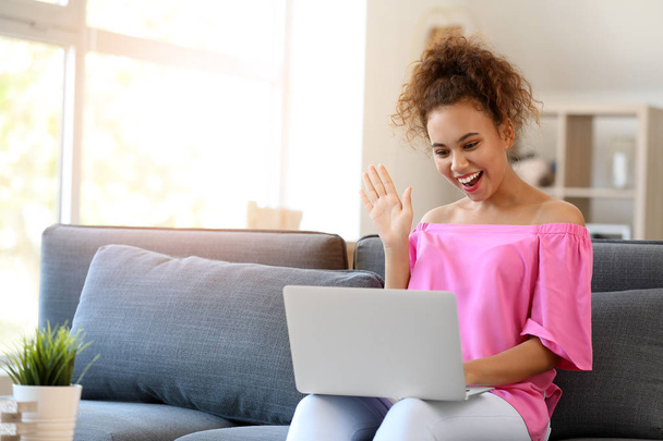 Retrato de la mujer afro-americana feliz con el ordenador portátil en casa
 - Foto, Imagen