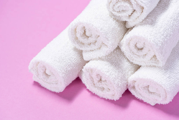 Toallas de rizo suavemente enrolladas para spa o masaje sobre un fondo rosa
 - Foto, imagen