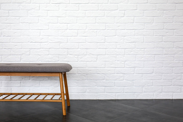 Удобная скамейка возле стены из белого кирпича
 - Фото, изображение