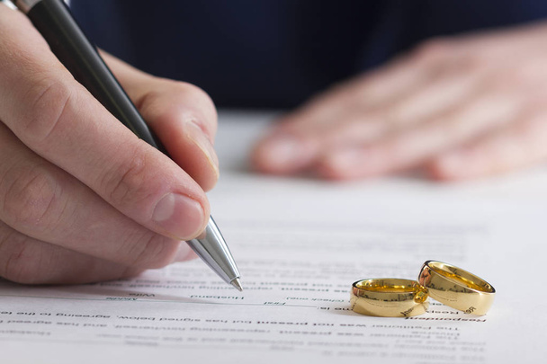 Hands of wife, husband signing decree of divorce, dissolution, canceling marriage, legal separation documents, filing divorce papers or premarital agreement prepared by lawyer. Wedding ring - Foto, afbeelding