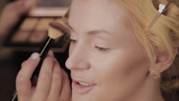 Professional make-up artist applies make-up photo of model to woman. - Materiał filmowy, wideo