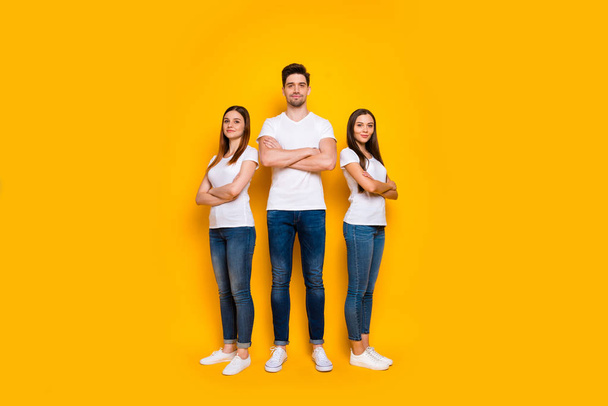 Full body photo of charming people with their arms crossed looking wearing white t-shirt denim jeans isolated over yellow background - Foto, Imagem