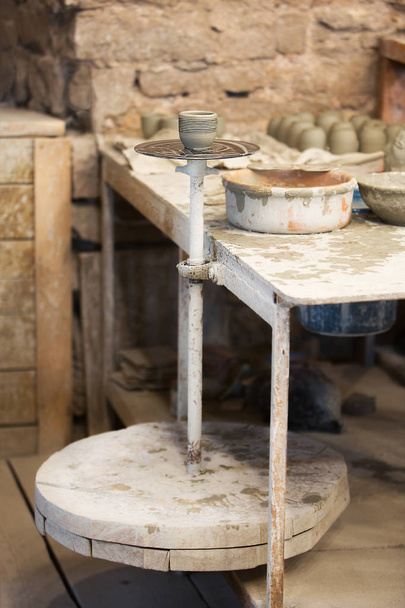 Clay pot on a pottery wheel in workshop - Photo, Image