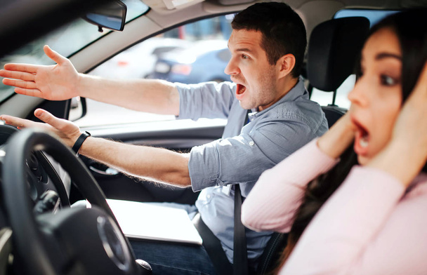 Male auto instructor takes exam in young woman. Stress during driving. Scared young woman touch head with hands. Instructor screaming and pointing forward. - Foto, Imagem