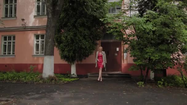 Photo model in a red dress walks on the old courtyard. - Felvétel, videó