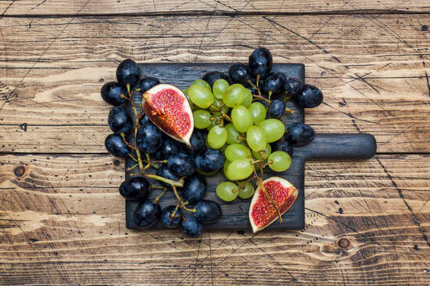Clusters of black and green grapes Kish Mish and figs on a wooden Board. Copy space. - Zdjęcie, obraz
