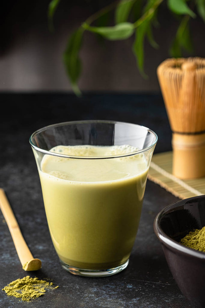 Matcha green tea latte in glass mug with whisk. - Foto, afbeelding