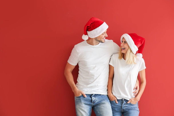 Szczęśliwa para w Santa kapelusze na kolorowym tle - Zdjęcie, obraz