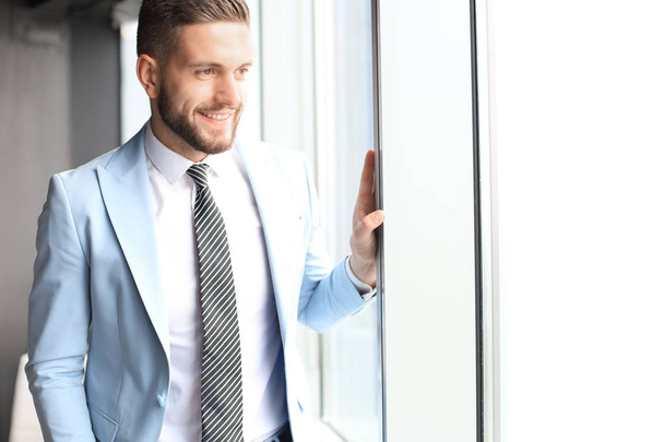 Modern business man in formalwear standing near window in the office - 写真・画像