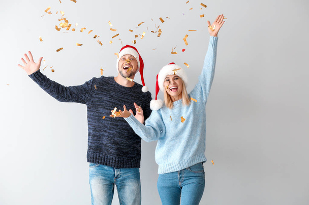 Onnellinen pari Santa hatut ja kuuluvat konfetti valolla taustalla
 - Valokuva, kuva