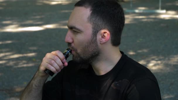 Young man vaping an electronic cigarette for the first time. getting annoyed by the smoke. - Séquence, vidéo