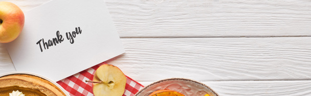 вид сверху на тыквенный пирог с благодарственной открыткой на деревянном белом столе с яблоками, панорамный снимок
 - Фото, изображение