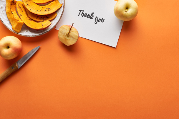 vista superior de calabaza, manzanas, cuchillo y tarjeta de agradecimiento sobre fondo naranja
 - Foto, Imagen