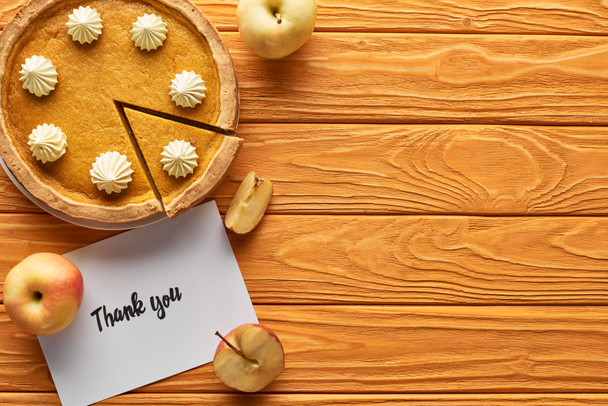 vista superior de pastel de calabaza con tarjeta de agradecimiento en la mesa de madera con manzanas
 - Foto, Imagen