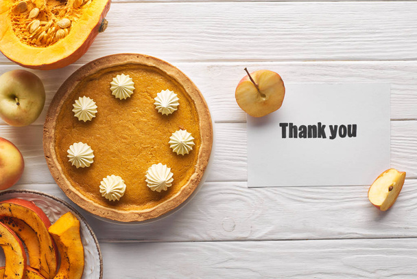 pohled na dýňový koláč s poděkováním s kartou na dřevěném bílém stolku s jablky - Fotografie, Obrázek