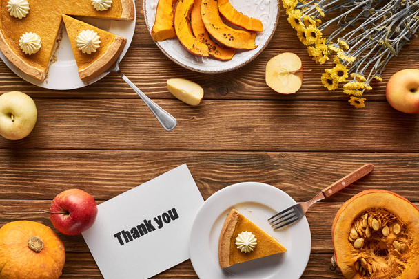 vista superior da torta de abóbora saborosa, flores, maçãs e cartão de agradecimento na mesa rústica de madeira
 - Foto, Imagem