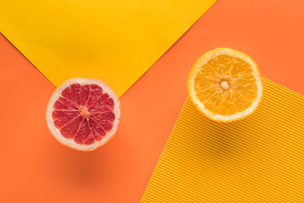 top view of orange and grapefruit on yellow and orange background with copy space - 写真・画像