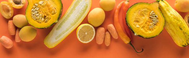 top view of yellow fruits and vegetables on orange background, panoramic shot - 写真・画像