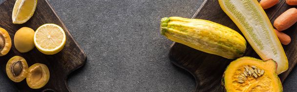vista superior de frutas e legumes amarelos em tábuas de corte de madeira em fundo cinza texturizado, tiro panorâmico
 - Foto, Imagem