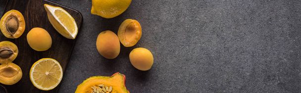 top view of pumpkin, apricots and lemon on wooden cutting boards on grey textured background, panoramic shot - Foto, immagini