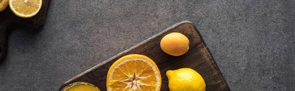 top view of yellow fruits on wooden cutting boards on grey textured background, panoramic shot - Photo, image