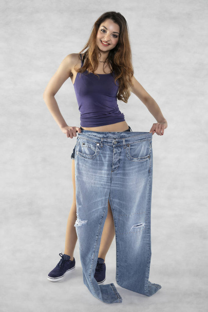 молода красива спортивна дівчина показує, скільки ваги вона втратила
 - Фото, зображення