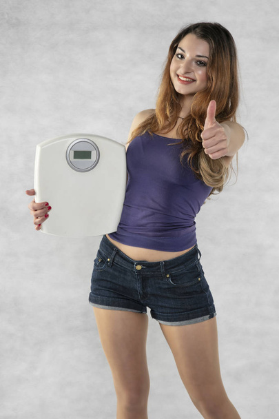 young beautiful girl with a weight, weight loss symbol - Zdjęcie, obraz