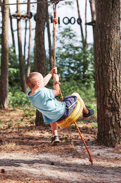 Joyeux garçon chevauchant sur la tyrolienne dans le parc de corde
 - Photo, image