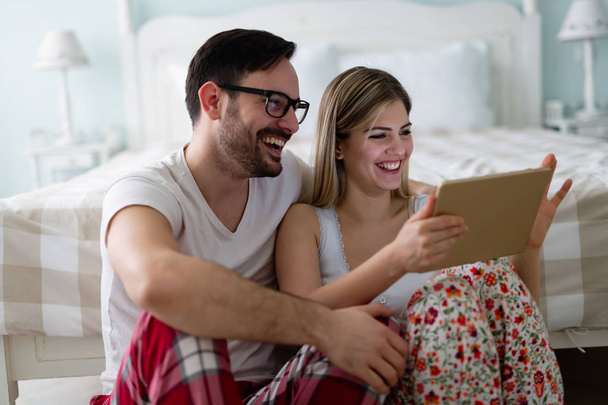 Young attractive couple using digital tablet in bedroom - Фото, зображення