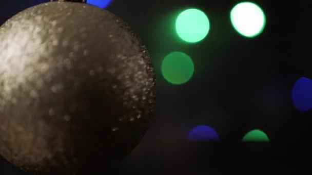 Rek focus op zilveren kerst bal op de voorgrond. Knipperende Kerstverlichting bokeh op de achtergrond. Close-up. - Video