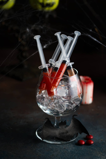 Coquetel Bloody Mary em seringa com web para celebração da festa de Halloween. fundo de pedra preta
. - Foto, Imagem