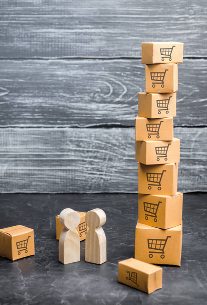 Two wooden people stand near a tower of boxes. buyer and seller, manufacturer and retailer. Business and commerce. Discussion of the terms of the trading deal, the purchase of goods and services. - Foto, Bild