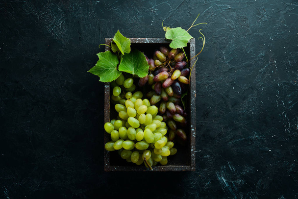 Fresh grapes with leaves on a black stone table. Top view. Free space for your text. - Valokuva, kuva