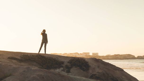 Woman in the top of a rock enjoying the beach view - Foto, Imagen