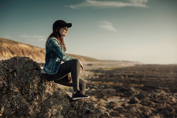 Beuutoful femme seule dans la plage assis sur les rochers
 - Photo, image